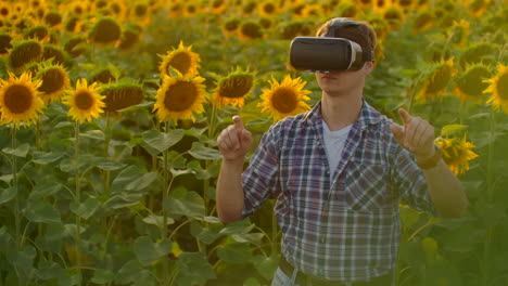 The-student-is-working-in-VR-glasses.-He-is-engaged-in-the-working-process.-It-is-a-beautiful-sunny-day-in-the-sunflower-field.